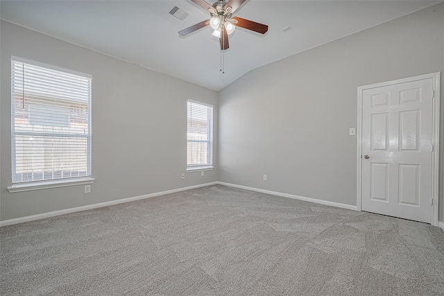 unfurnished room with ceiling fan, visible vents, vaulted ceiling, carpet floors, and baseboards
