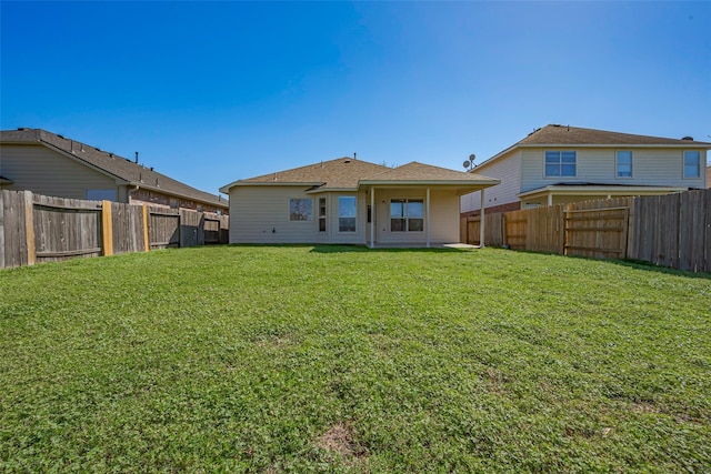 rear view of property featuring a lawn and a fenced backyard