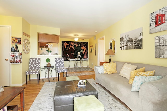living area featuring a ceiling fan, baseboards, and wood finished floors