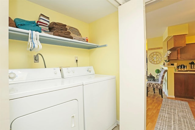 washroom featuring separate washer and dryer, laundry area, and light wood-style floors