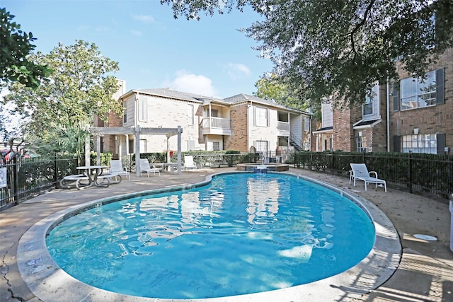 view of swimming pool with fence, a pergola, a pool with connected hot tub, and a patio