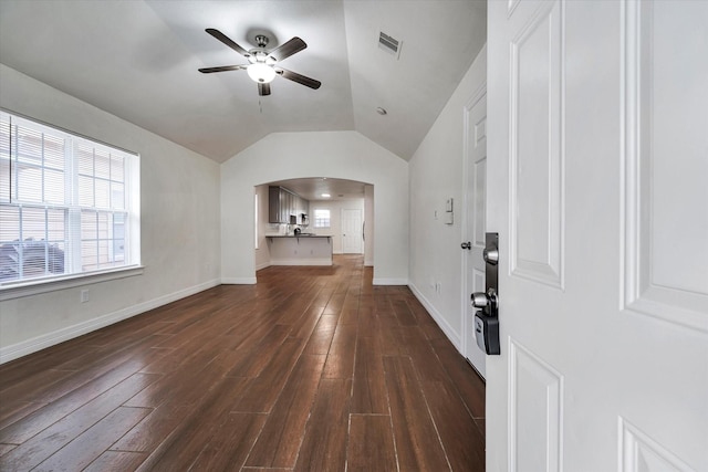 unfurnished living room featuring arched walkways, dark wood finished floors, a ceiling fan, vaulted ceiling, and visible vents