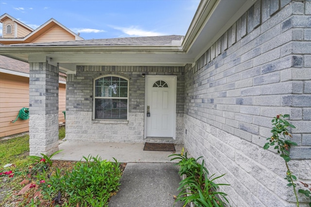 doorway to property featuring a porch and a shingled roof
