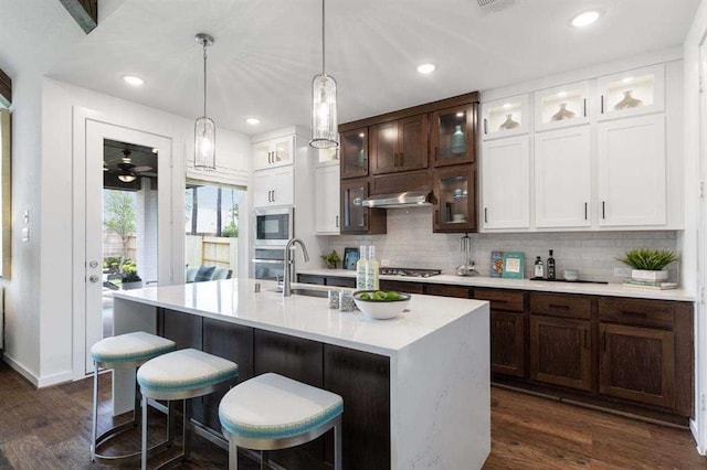 kitchen featuring a breakfast bar area, tasteful backsplash, dark wood finished floors, light countertops, and white cabinetry