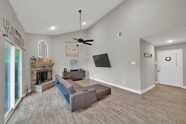 living area with ceiling fan, visible vents, a brick fireplace, baseboards, and light wood-style flooring