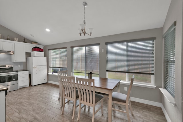 dining space featuring baseboards, an inviting chandelier, vaulted ceiling, and light wood-style floors