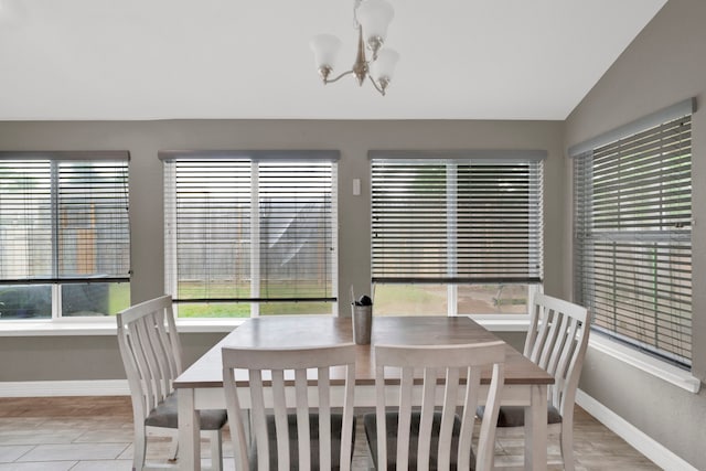 dining area featuring baseboards, vaulted ceiling, and a notable chandelier
