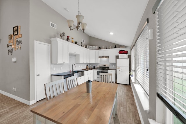 kitchen featuring electric range, light wood finished floors, high vaulted ceiling, freestanding refrigerator, and visible vents