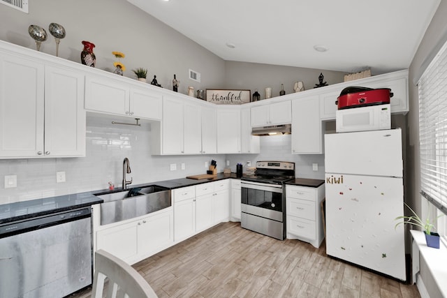 kitchen with appliances with stainless steel finishes, a sink, lofted ceiling, under cabinet range hood, and visible vents
