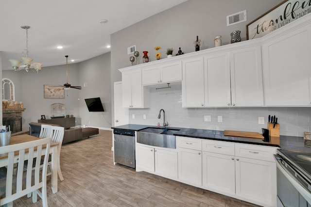 kitchen with appliances with stainless steel finishes, a sink, ceiling fan with notable chandelier, backsplash, and visible vents