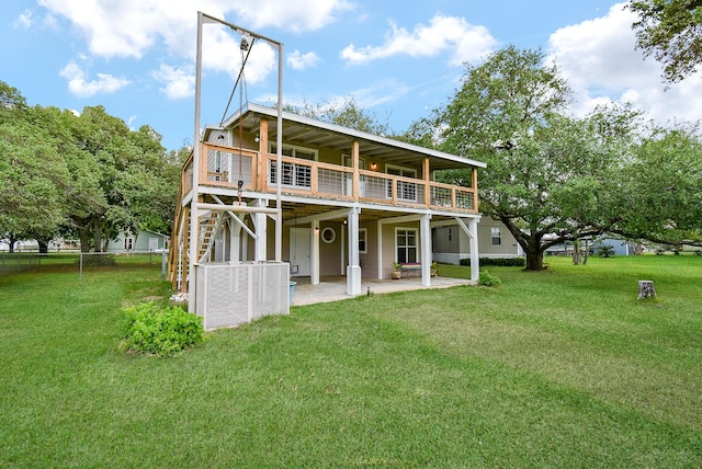 rear view of house featuring fence, a wooden deck, stairway, a lawn, and a patio