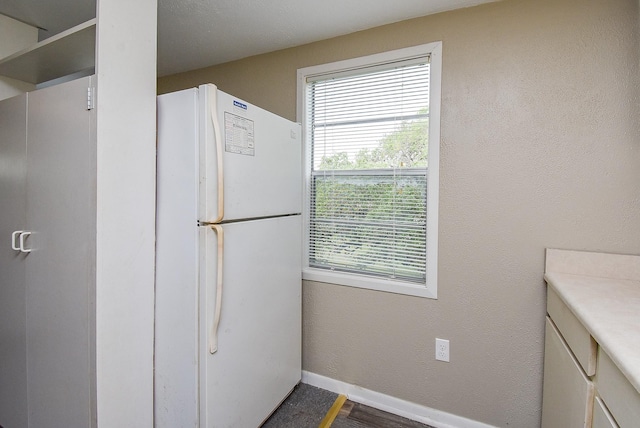 kitchen featuring baseboards and freestanding refrigerator