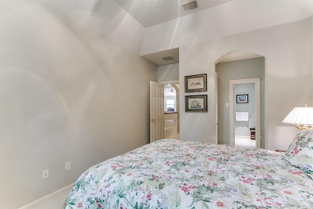 bedroom with carpet floors, arched walkways, baseboards, and visible vents