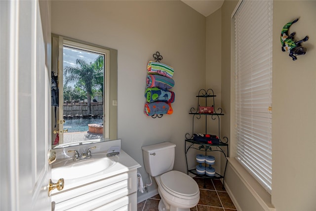 half bathroom featuring tile patterned floors, baseboards, vanity, and toilet