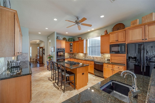 kitchen featuring a ceiling fan, a sink, arched walkways, and black appliances