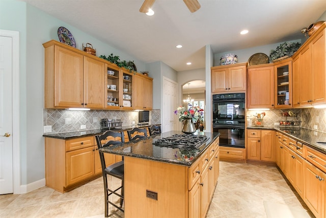 kitchen featuring a breakfast bar area, a center island, tasteful backsplash, arched walkways, and black appliances