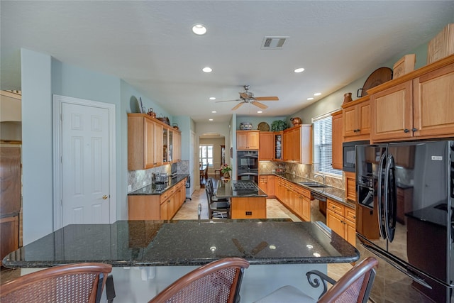 kitchen featuring a sink, arched walkways, a center island, backsplash, and black appliances