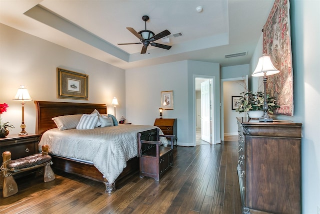 bedroom featuring visible vents, baseboards, dark wood finished floors, and a raised ceiling