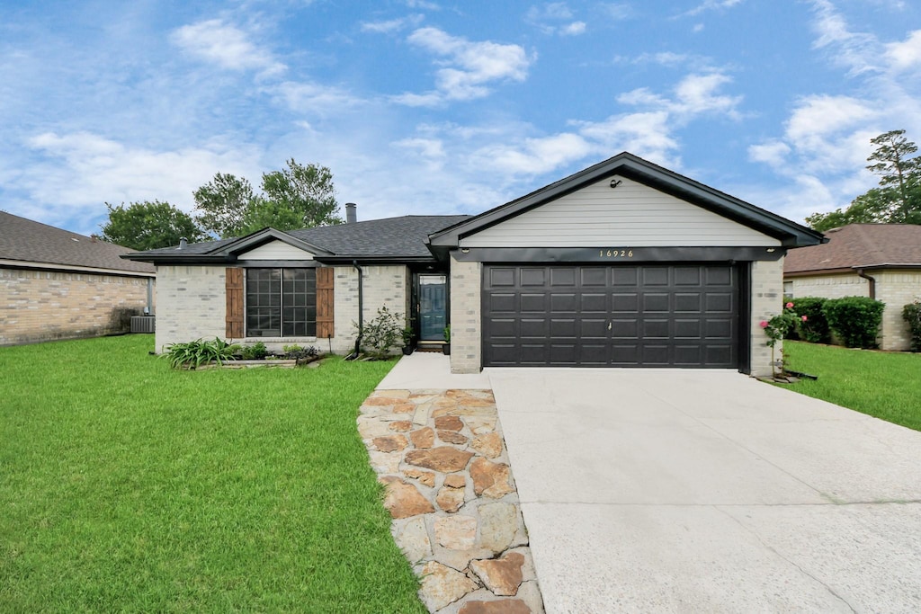 16926 Hummingbird, Conroe, TX 77385 - single story home with driveway, a garage, brick siding, central AC, and a front lawn