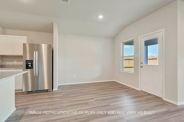 interior space featuring stainless steel fridge, white cabinets, light wood-style floors, and lofted ceiling