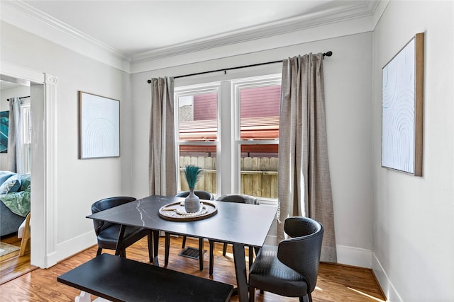 dining room featuring crown molding, baseboards, and light wood-style flooring