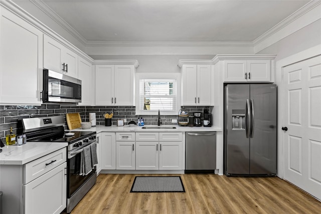 kitchen with light countertops, stainless steel appliances, white cabinets, and a sink