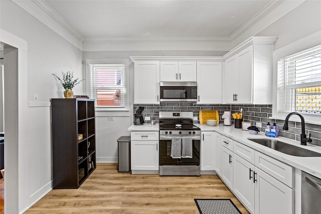 kitchen featuring plenty of natural light, a sink, white cabinets, and stainless steel appliances