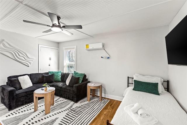 living room with baseboards, a wall mounted air conditioner, a ceiling fan, and wood finished floors