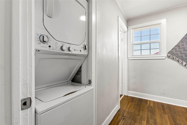clothes washing area featuring a textured wall, laundry area, baseboards, stacked washer / dryer, and dark wood-type flooring