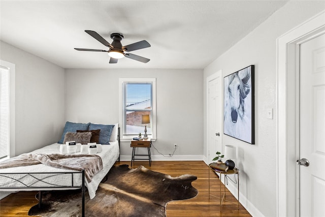 bedroom with a ceiling fan, baseboards, and wood finished floors