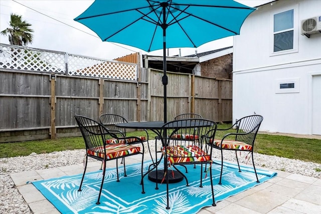 view of patio with fence, outdoor dining space, and ac unit