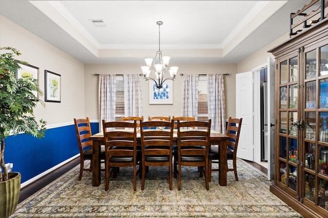 dining space featuring crown molding, a tray ceiling, wood finished floors, and a chandelier