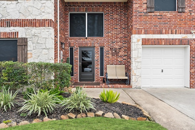 view of exterior entry featuring concrete driveway, brick siding, and stone siding