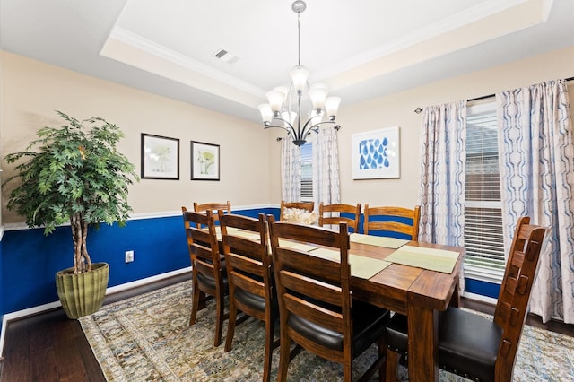 dining room with crown molding, visible vents, wood finished floors, a tray ceiling, and a chandelier