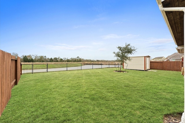 view of yard featuring a fenced backyard, an outdoor structure, a water view, and a storage shed