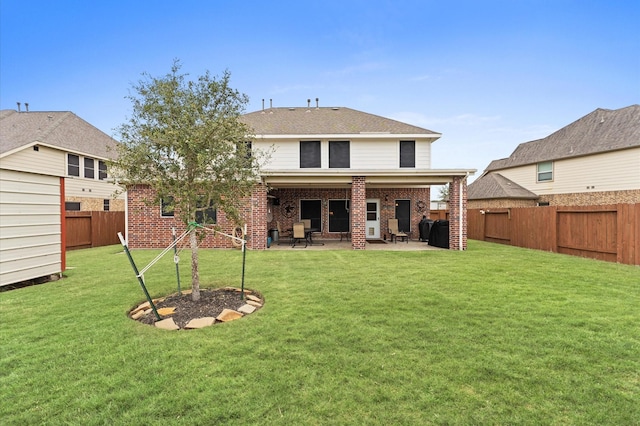 back of property with a fenced backyard, a patio, a yard, and brick siding