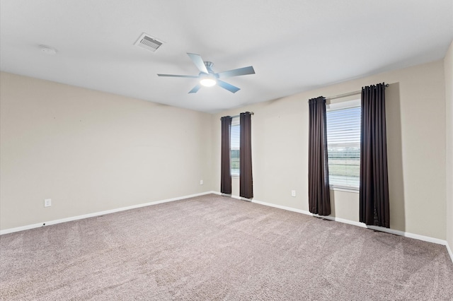 carpeted empty room featuring ceiling fan, visible vents, and baseboards