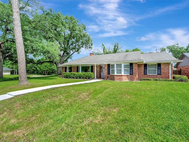 ranch-style home with brick siding, a front lawn, and a chimney