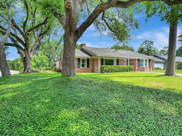 single story home with brick siding, a front yard, and a chimney