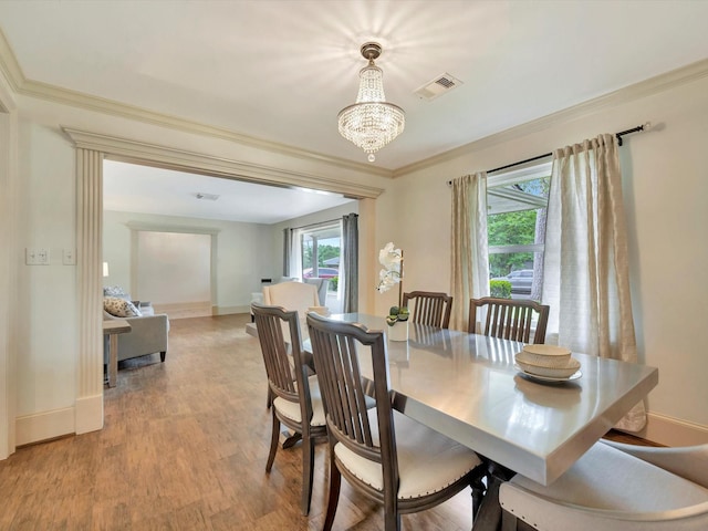 dining space with light wood-style flooring, baseboards, ornamental molding, and a chandelier
