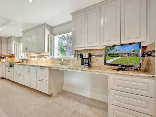 kitchen with decorative backsplash, light stone counters, white cabinetry, a sink, and light tile patterned floors