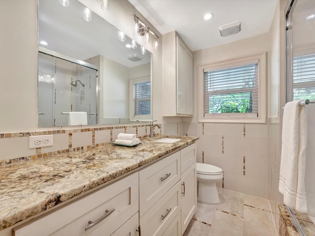 full bath featuring plenty of natural light, toilet, a shower stall, vanity, and tile walls