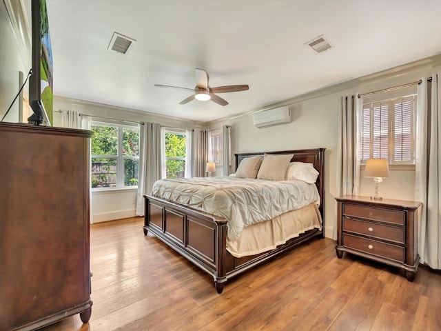 bedroom with a wall mounted AC, hardwood / wood-style flooring, ceiling fan, and baseboards
