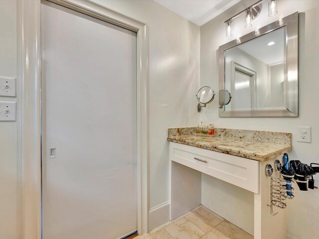 bathroom featuring marble look tiles, baseboards, and vanity