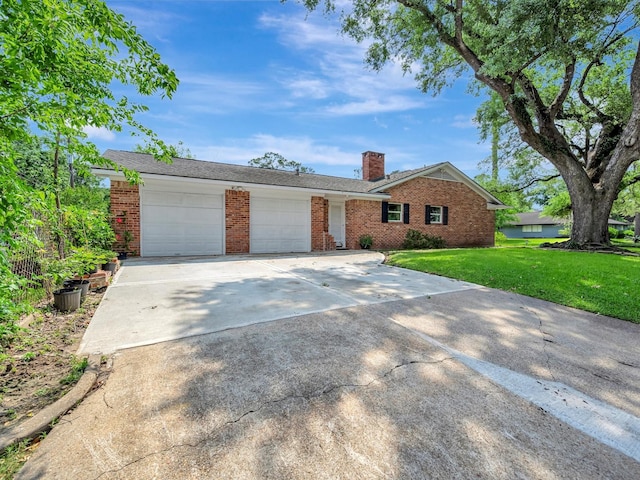 ranch-style house featuring brick siding, a chimney, an attached garage, a front yard, and driveway