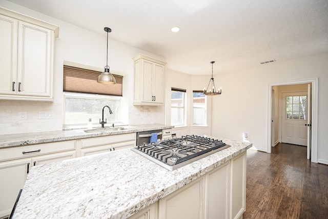 kitchen featuring dark wood-style flooring, tasteful backsplash, a sink, light stone counters, and stainless steel gas stovetop