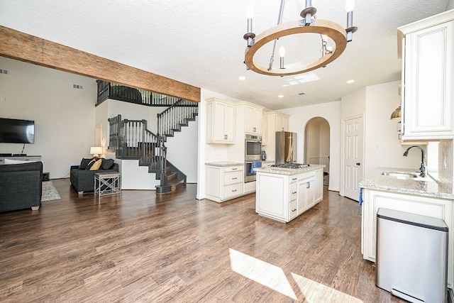 kitchen featuring an inviting chandelier, dark wood-type flooring, arched walkways, a sink, and appliances with stainless steel finishes