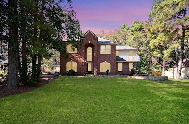 view of front facade with a lawn and brick siding