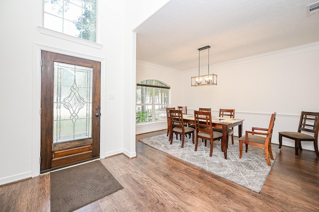 foyer entrance with an inviting chandelier, ornamental molding, baseboards, and wood finished floors