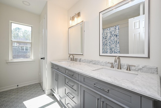 bathroom featuring baseboards, a sink, and double vanity